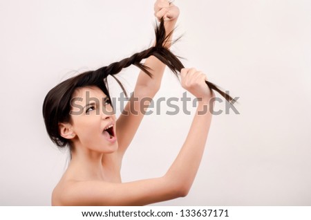 Beautiful brunette girl with long hair. Young attractive woman screaming pulling her hair.