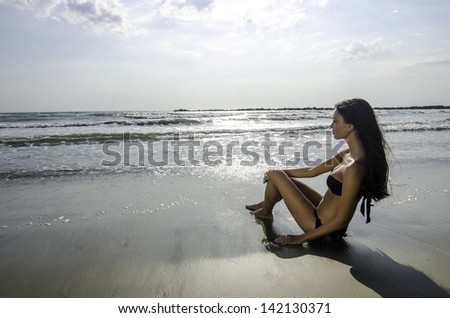 Beautiful perfect brunette woman enjoying summer on the beach and sea waves, girl looking at the beautiful scene