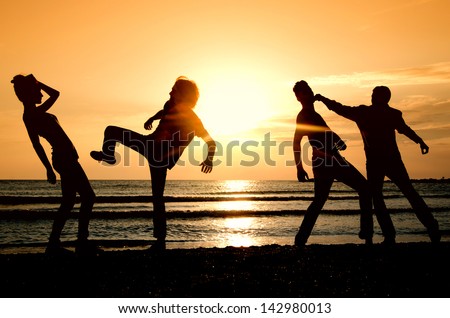 Group of happy people parting on the beach at sunrise, getting fit in the morning, people fighting