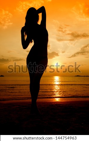 Silhouette of a sensual woman at sunrise on the beach, sexy body, perfect figure