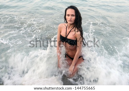 Perfect woman in swimsuit enjoying her time on the beach, waves hit her fit body