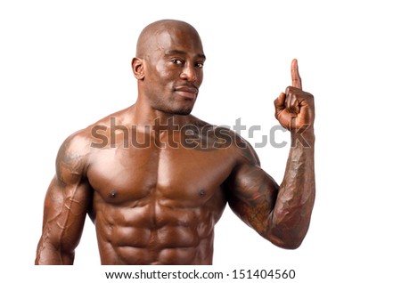 Black bodybuilder smiling and pointing. Black bodybuilder topless, showing his muscles. Strong man with perfect abs, shoulders,biceps, triceps and chest. Isolated on white background