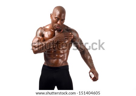 Black bodybuilder pouring oil on his muscles. Black bodybuilder topless, showing his muscles. Strong man with perfect abs, shoulders,biceps, triceps and chest. Isolated on white background