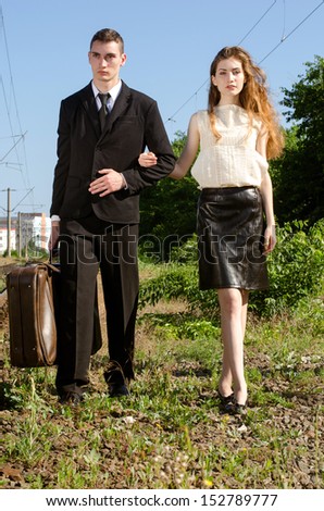 Couple in a train station waiting for their train to come to go in honeymoon vacation