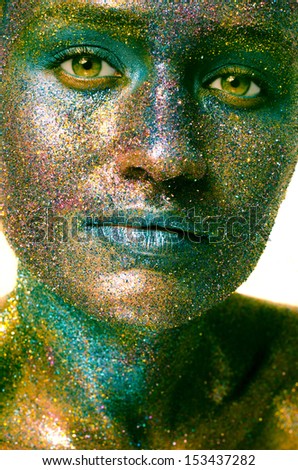 Beautiful face of a woman covered in glitter. Close up of a woman\'s face covered in shades of green glitter
