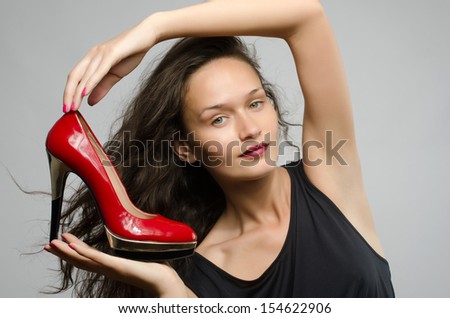 Woman in love with her high heel shoes. Beautiful girl holding her red sexy stiletto shoe.