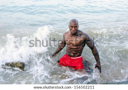 Strong bodybuilder fighting waves,working out with the nature power. Strong man with perfect abs, pecs shoulders,biceps, triceps