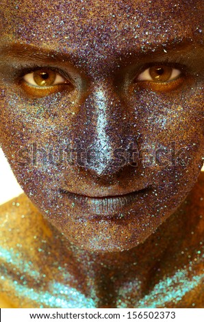 Beautiful face of a woman covered in glitter Close up of a woman\'s face covered in yellow glitter