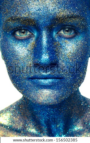 Beautiful face of a woman covered in glitter Close up of a woman\'s face covered in blue glitter