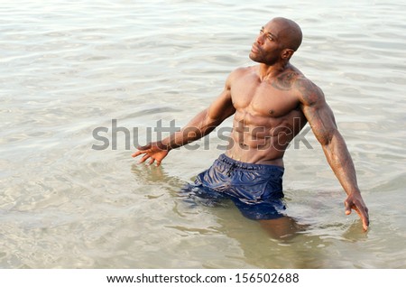 Black bodybuilder relaxing in the water after a hard workout during a summer vacation. Strong man with perfect abs, pecs shoulders,biceps, triceps
