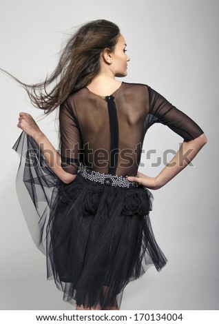 Girl posing fashion from the back wearing a lace black dress. Young woman with see through dress on the back.