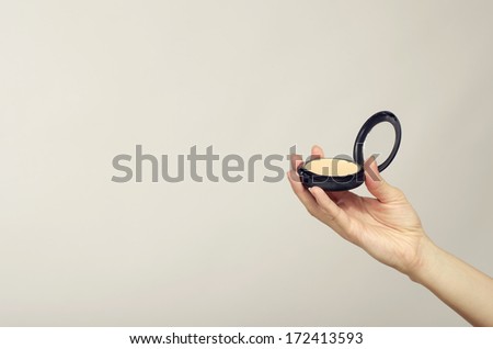 Close up of a woman hand holding a make up mirror, make up powder