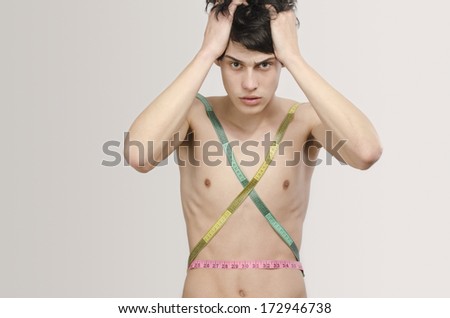 Skinny young man posing fashion with a centimeter, anorexic look. Slim body