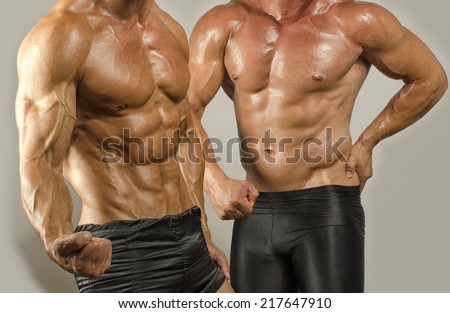 Fit body versus fat body, flexing muscles. Two men showing their biceps,abs, chest and shoulders in a contest