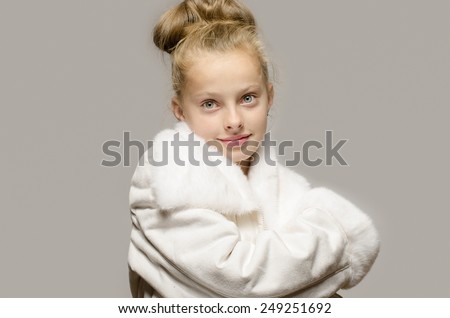 Girl wearing a white long coat and looking like snow white, beautiful kid worming up in for the winter time