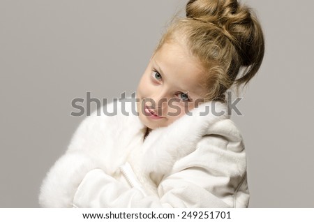 Girl wearing a white long coat and looking like snow white, beautiful kid worming up in for the winter time