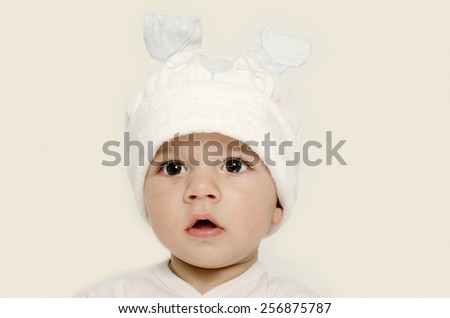 Innocent baby wearing a white hat looking adorable. Kid dressed for winter, lovely newborn. Adorable baby portrait looking curious.  Baby dressed as a funny bunny with a white hat with rabbit ears