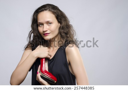 Woman in love with her high heel shoes. Beautiful girl holding her red sexy stiletto shoe. Lady shopping for shoes