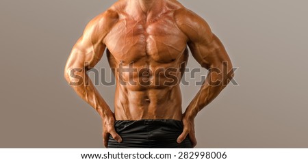 Close up on perfect abs. Strong bodybuilder with six pack.Strong bodybuilder man with perfect abs, shoulders,biceps, triceps and chest, personal fitness trainer flexing his muscles
