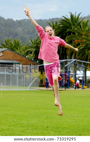 Young teenage girl jumping for joy, holding certificate in hand