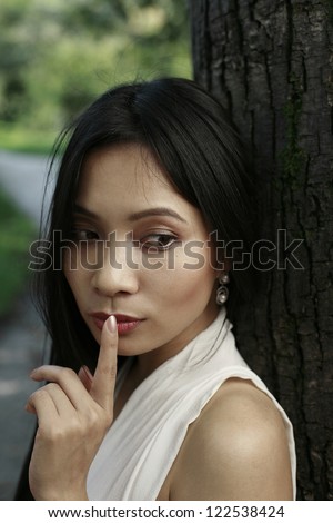 asian girl with finger on lips, telling a secret