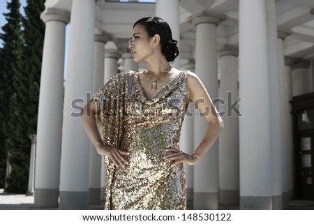 Beautiful asian woman in golden evening dress, Vietnam, looking away
