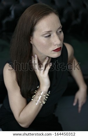 beautiful young business woman in black looking up , leaning on black leather couch