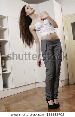 girl in pants and corset looking up on high heels