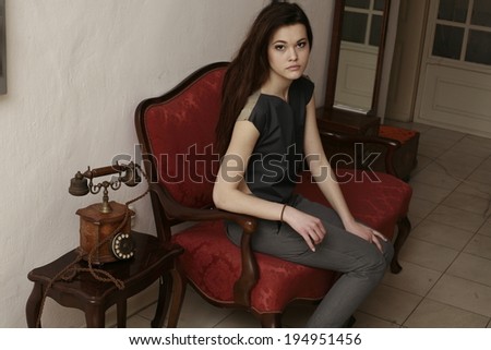beautiful young girl sitting on the sofa, stylish furniture in the old apartment
