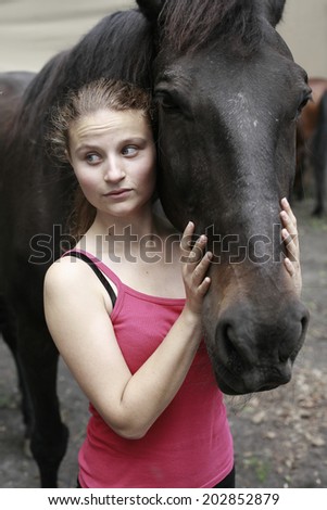 portrait of a beautiful girl with a black horse , image of beautiful young woman and black horse, inside fence for horses