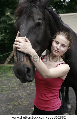 portrait of a young woman with a black horse , image of beautiful young woman and black horse, inside fence for horses