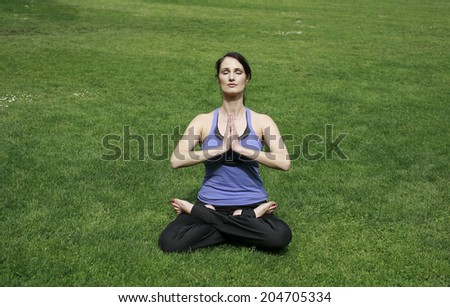 woman meditating on grass, young woman sitting in a lotus flower and meditating on the lawn