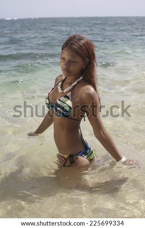 Latina in bikini posing water, girl in swimsuit wearing necklace walking out of water on sandy beach