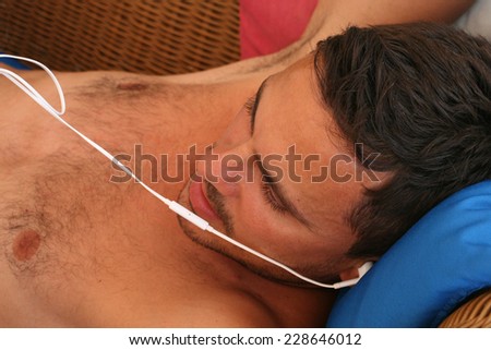 young man lying with head phones ,young man with head phones talking over cell phone