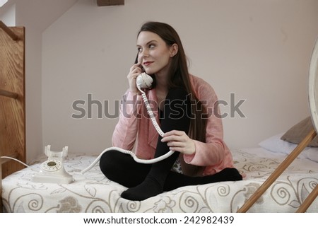 girl on the phone the bed happy dreamy beauty girl hugging her legs while siting in bed against the wooden wall