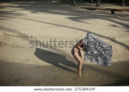 blond girl in bikini  on the beach playing with scarf ,  young woman in bikini on a sandy sunny beach!