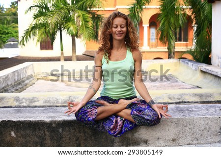 A young woman is in a warrior yoga pose on a roof top in the city , Girl with  red hair, portrait on the roof