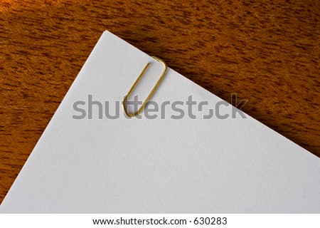 Paperclipped pages lying on a wooden desk - pages are blank so that you can add your own text.