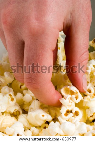 Hand taking a piece of popcorn from a bowl.