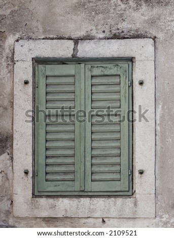 Old rustic window with the green shutters closed.
