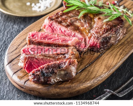 Medium rare Ribeye steak or beef steak on the wooden tray with herbs.
