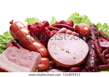 Meat and sausages on lettuce leaves. Isolated on white background from above.