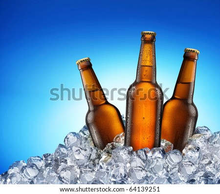 Three beer bottles getting cool in ice cubes. Isolated on a blue. File contains a path to cut