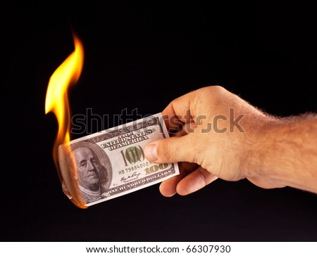 burning dollar in hand isolated on a black