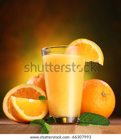 Still life: oranges and glass of juice on a wooden table.