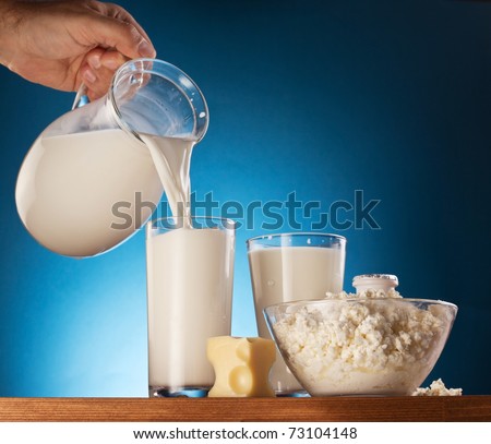 Milk products. Man hand is pouring milk from jar into glass.