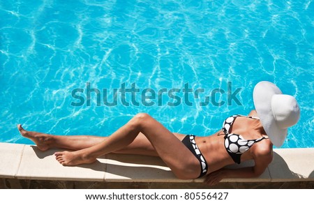 Young woman sitting on the ledge of the pool.