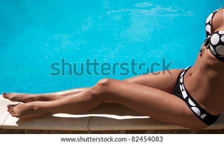 Young woman sitting on the ledge of the pool.