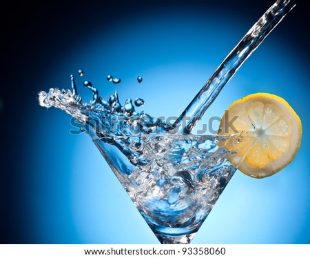 Splash from pouring martini into the glass. Object on a blue background.