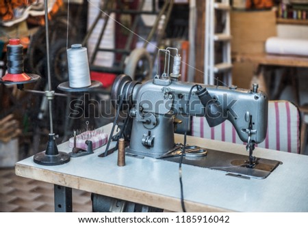 Old-fashined sewing machine in the sewing room. Working place of sewer.